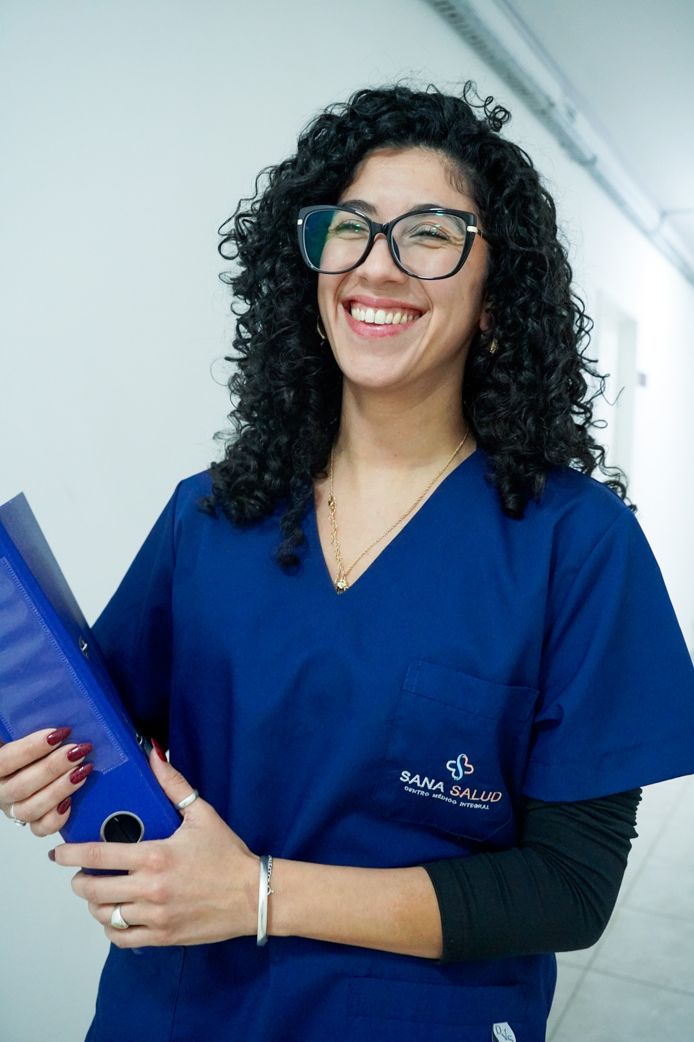 Integrante del equipo de Sana Salud sonriendo en el pasillo del centro médico.